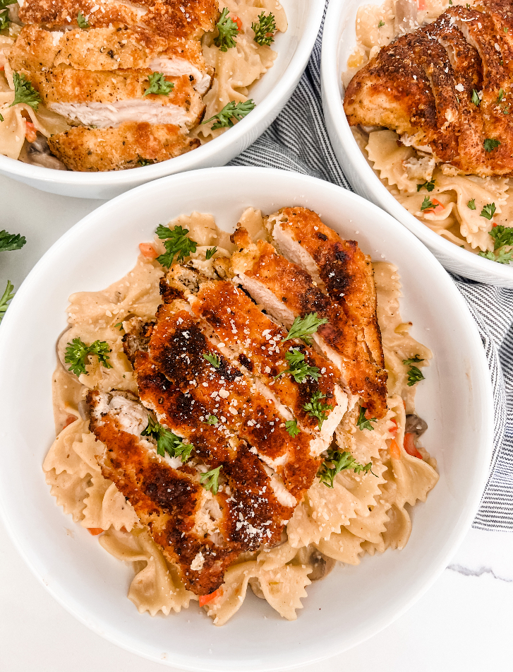 This Lightened Up Copycat Cheesecake Factory Louisiana Chicken Pasta is a lightened up dish from the Cheesecake Factory-packed with mushrooms, onions, and bell peppers, bow tie pasta, then smothered in a creamy cajun sauce, and topped with a Parmesan crusted chicken breast! It’s a simple skillet meal that comes together quickly and is loaded with goodness!